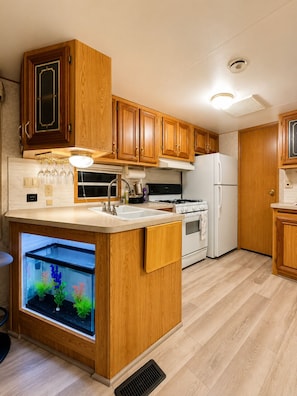 A kitchen with wooden cabinets, a built-in sink, a stove, and a fish tank. - Cozy Naples Retreat w/ Lanai - Near Beaches (Naples)
