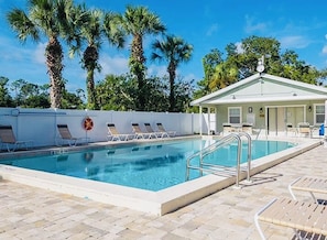 A swimming pool with lounge chairs, a lifebuoy, and a building with a white roof.