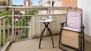 A balcony with a table and a chair, a view of buildings, and a clear sky. - Room-elegant Central Apartment Room in A (Kista)