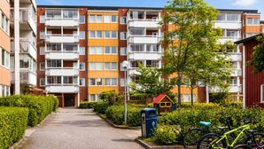 A multi-story residential building with balconies, a small playhouse, and bicycles parked outside. - Room-elegant Central Apartment Room in A (Kista)