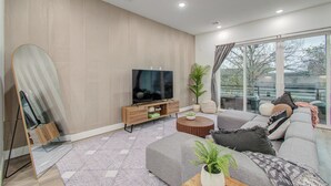 A modern living room with a large flat-screen TV, a sofa set, a coffee table, and a large mirror.