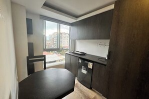 Eine moderne Küche mit Esstisch, Kühlschrank und Fenster mit Blick auf Gebäude.