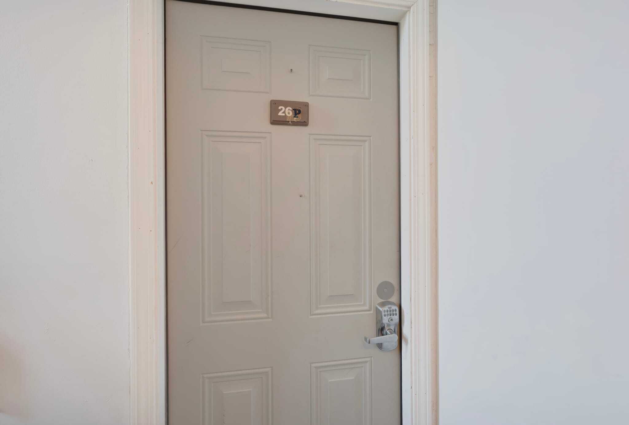 Une porte avec une plaque portant le numéro « 26P » et un système de verrouillage à clavier.
