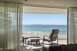 Ein Zimmer mit Blick auf den Strand, ein Tisch, ein Stuhl und ein Sofa.