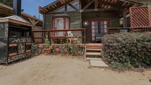 Una cabaña rústica de madera con un porche, chimenea y plantas en macetas.