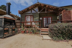 Une cabane en bois rustique, dotĂ©e dâun porche, dâune cheminĂ©e et de plantes en pot.