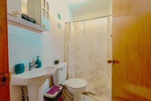A bathroom with a sink, toilet, and shower curtain. - Lovely 2-bedroom cabin in Algarrobo perfect for a relaxing getaway (Algarrobo)