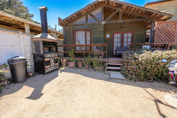 Une cabane en bois rustique, dotĂ©e dâune cheminĂ©e, dâun porche et de plantes en pot.