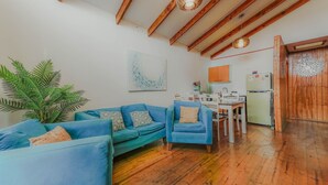 Un espacio de estar con techo de madera, una mesa de comedor y un refrigerador.