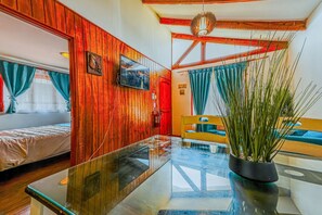 A room with wooden paneling, a glass table, a bed, a television, and a plant. - Lovely 2-bedroom cabin in Algarrobo perfect for a relaxing getaway (Algarrobo)
