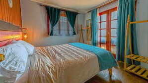 Un dormitorio con cama, cortinas, una escalera de madera y una ventana con vistas.