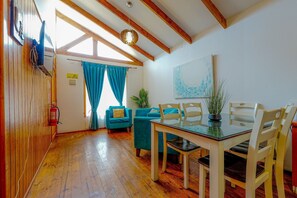 A dining area with a wooden ceiling, a table with chairs, and a blue curtain. - Lovely 2-bedroom cabin in Algarrobo perfect for a relaxing getaway (Algarrobo)