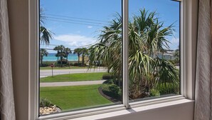 Ein Fenster mit Blick auf einen gepflegten Rasen, Palmen und ein Stoppschild.