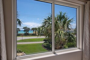 Ein Fenster mit Blick auf einen gepflegten Rasen, Palmen und ein Stoppschild.