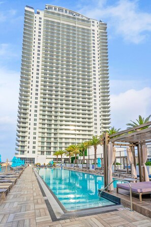 Un hotel moderno con piscina, sillas de descanso y palmeras.