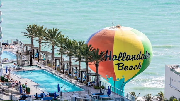 Ein Resort mit Pool, Liegestühlen und einem bunten, strand-inspirierten Heißluftballon.
