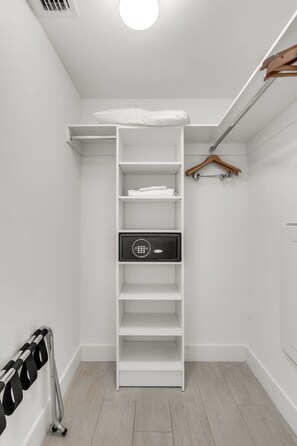 Un vestidor con estantes blancos, una barra para colgar ropa y un zapatero.