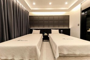 Una habitación de hotel con dos camas, un cabecero con diseño de cuadrícula, una mesita de noche y una puerta.