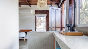 Una cocina con una isla de concreto, armarios de madera y una ventana que da a la calle.