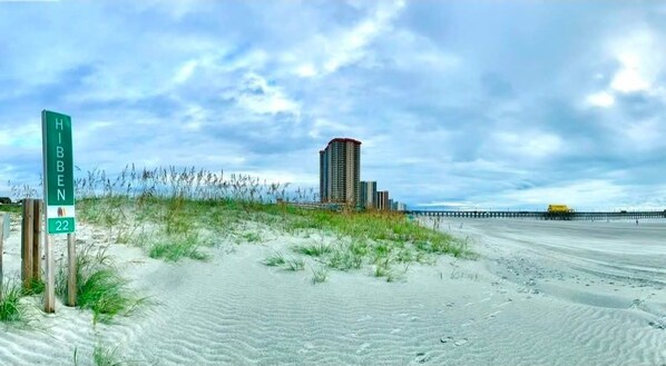 A beach with a sign for 'HIBBEN 22' and a tall building in the background. - Cozy Beach Bungalow located in Myrtle Beach, SC (Myrtle Beach)