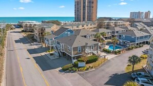 Ein Hotel an der Küste mit mehrstöckigen Gebäuden, einem Schwimmbad und einer Straße, die zum Strand führt.