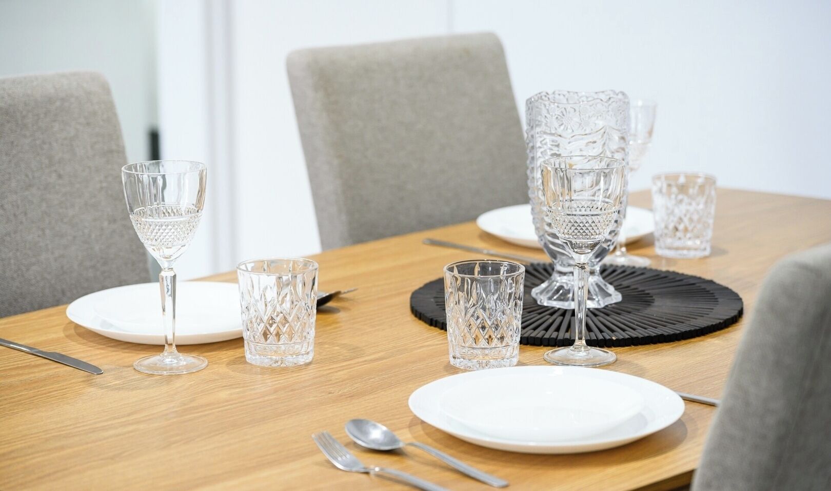 A dining table set with clear glassware, plates, and cutlery.