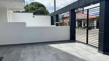 Un bâtiment moderne doté d’un toit plat, d’un mur blanc et d’un portail en métal noir.