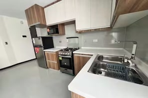 A modern kitchen with white countertops, wooden cabinets, a stainless steel sink, and a built-in oven. - habitacion 
-bedroom apartment in Cochabamba perfect for your stay (Cochabamba)