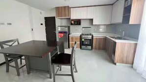 Une cuisine moderne dotée d’un coin repas, comprenant une table et des chaises, un réfrigérateur, un four et des placards.