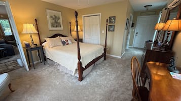 Un dormitorio con cama con dosel, ventilador de techo, escritorio con silla y puerta que da a otra habitación.