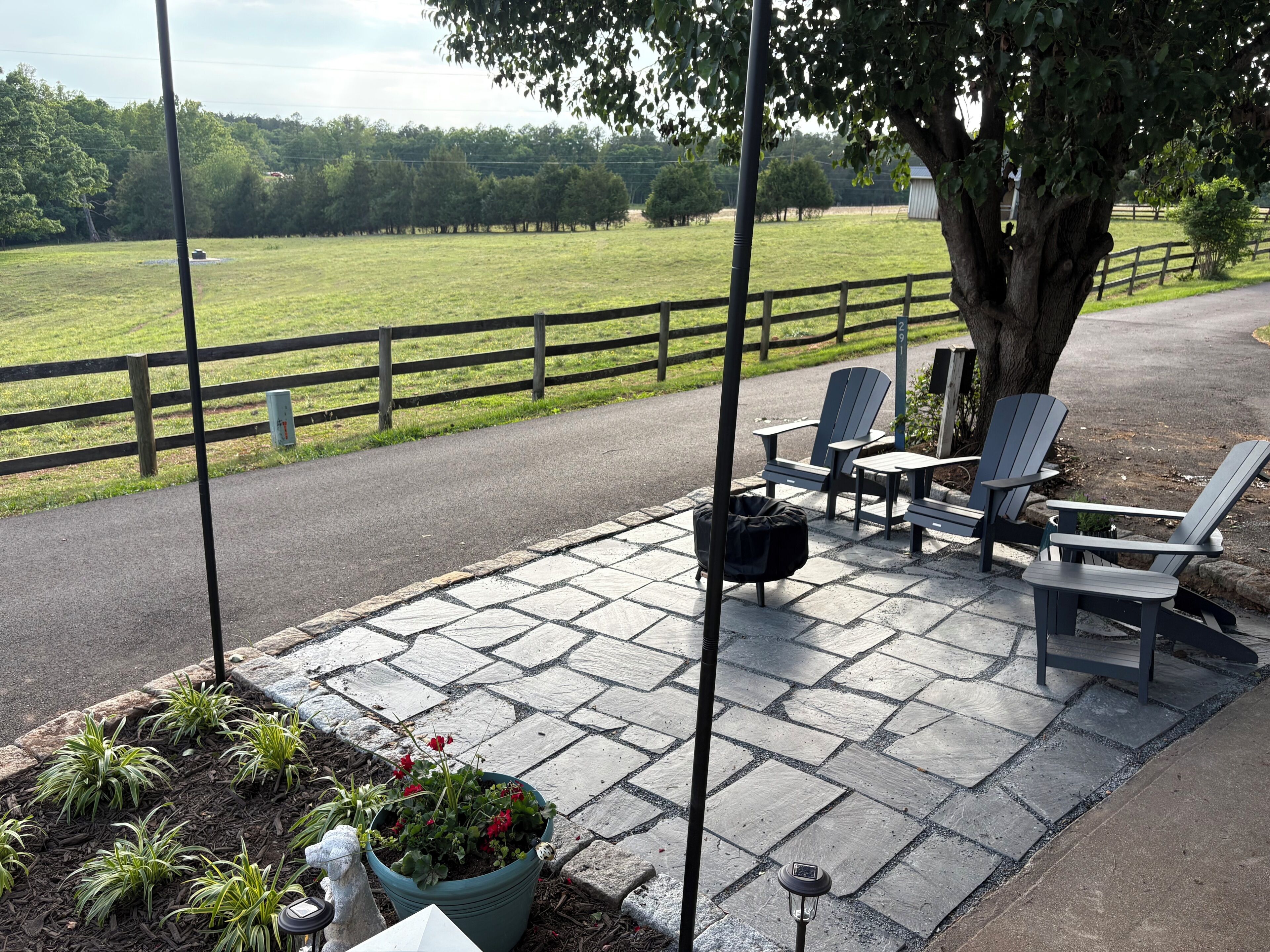 A patio with Adirondack chairs, a potted plant, and a lamp.