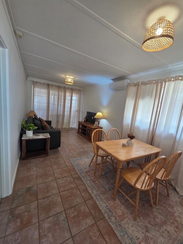 Una sala de estar con sofá, televisión y comedor con mesa y sillas.