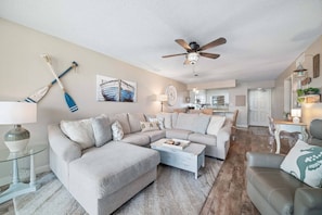 A living room with a sectional sofa, a coffee table, and a ceiling fan. - Seaside Beach and Racquet 5216 | BeachFront + Pool (Orange Beach)