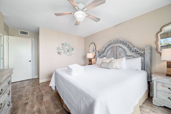 A bedroom with a bed, a ceiling fan, a dresser, and a nightstand. - Seaside Beach and Racquet 5216 | BeachFront + Pool (Orange Beach)