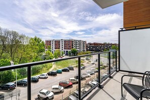 A balcony with a view of a parking lot and buildings.