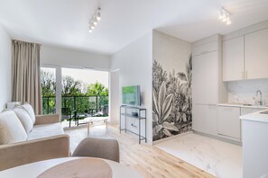 A modern apartment with a balcony, a dining area, a kitchen, and a living room.