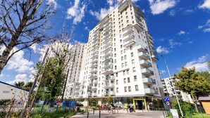 Ein mehrstöckiges Wohngebäude mit Balkonen, einem Fußgängerweg und blauem Himmel.