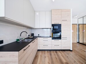 Cozinha moderna com bancada preta, armários de madeira e eletrodomésticos embutidos.