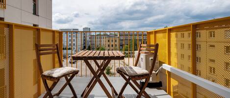 Un balcón con dos sillas de madera y una mesa, con vistas a una zona residencial.