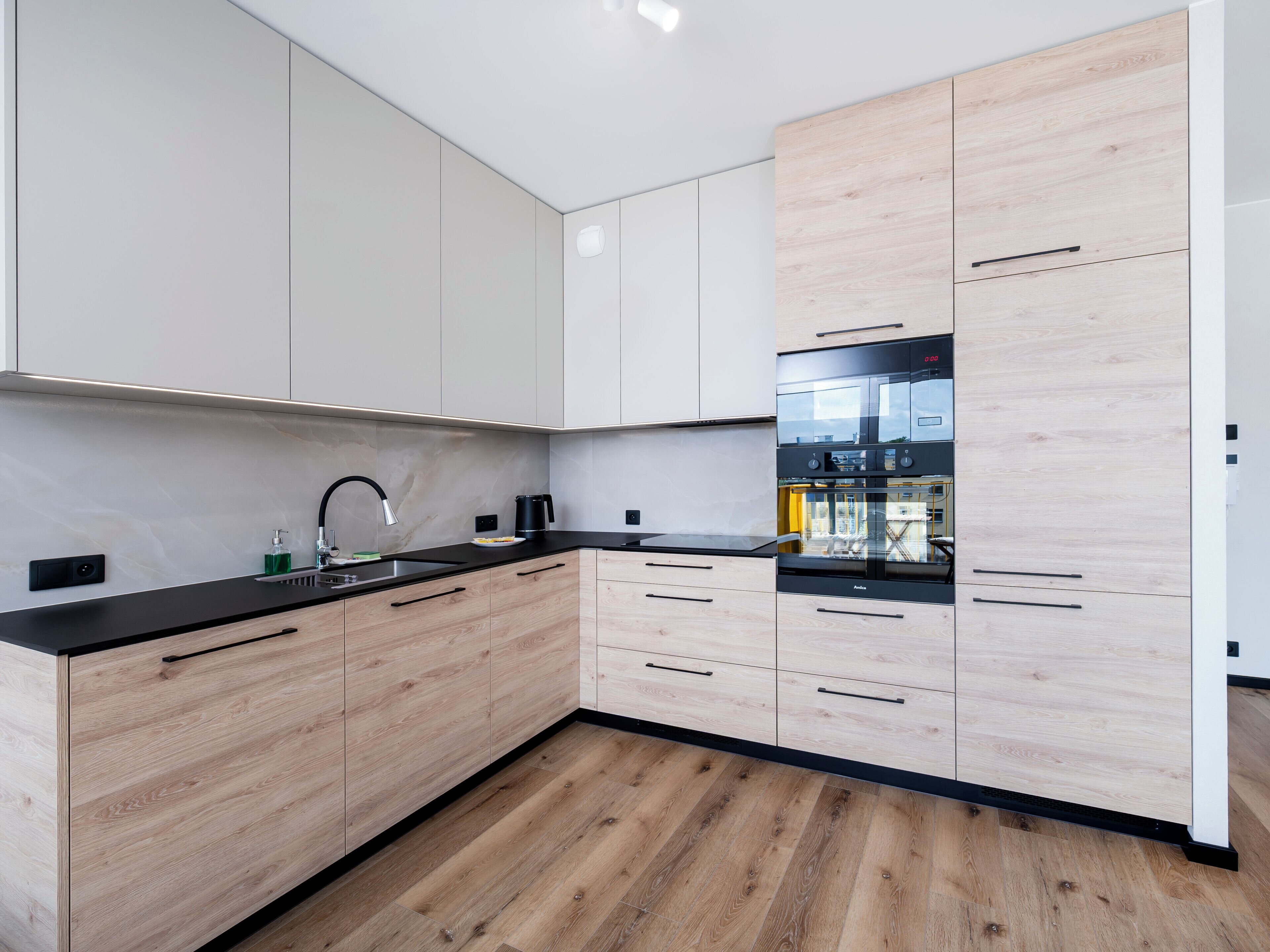 A modern kitchen with wooden cabinets, a black countertop, and a built-in oven.