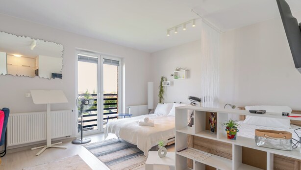 Een moderne slaapkamer met een bed, nachtkastjes, een spiegel en uitzicht op de omgeving.