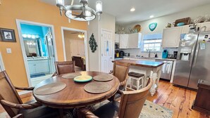 A dining area with a round table, chairs, and a chandelier. - Coastal 3BR Cottage w/ Pool Access & EV Charger | The Rookery 900 Fort Morgan (Gulf Shores)
