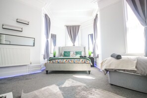 A bedroom with a bed, a sofa, a radiator, a mirror, and curtains. - Spacious Apt with Free Parking (Folkestone)