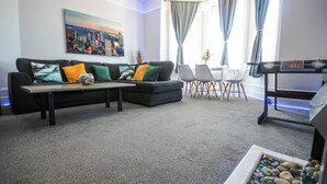 A living room with a sectional sofa, a coffee table, a small table with chairs, and a decorative rock arrangement. - Spacious Apt with Free Parking (Folkestone)