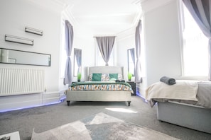 A bedroom with a bed, a sofa, a radiator, and a window with curtains. - Spacious Apt with Free Parking (Folkestone)