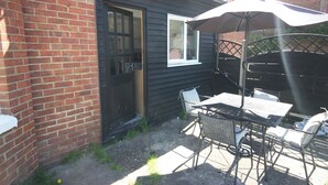 A patio with a table and chairs, a door, and a window. - Spacious Apt with Free Parking (Folkestone)