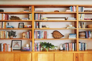 Une bibliothèque avec des livres, des objets de décoration et un tableau encadré.