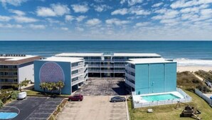 Een hotel met zwembad, parkeerplaats en uitzicht op zee.