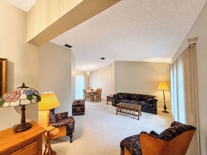 Ein großzügiges Wohnzimmer mit Essbereich, einer Couch, einem Couchtisch und einer Lampe.