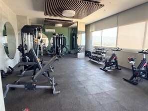 Ein Fitnessstudio mit Trainingsgeräten, großen Fenstern und einem Spiegel.